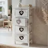 A white chest of drawers with heart cutouts in a room with a sofa and a macrame wall hanging. Anteprima dell’immagine prodotto