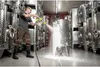 A man is cleaning a large stainless steel tank with a pressure washer in a winery. Produktbild-Vorschau