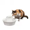 A calico cat drinks water from a white pet fountain. Produktbild-Vorschau