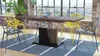 A dining table with chairs in a modern loft-like setting with large windows. Produktbild-Vorschau