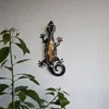 A decorative gecko with LED lights mounted on a textured white wall, next to a potted plant. Produktbild-Vorschau