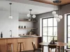 A modern kitchen and dining area with wooden cabinets, a kitchen island with stools, and a dining table with chairs, illuminated by pendant lights. Produktbild-Vorschau