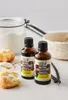 Two bottles of vanilla extract are displayed on a surface with baking ingredients like flour and vanilla pods. Náhľad obrázku produktu