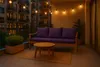 A balcony at dusk with a sofa, coffee table, and string lights. Náhľad obrázku produktu