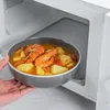 A hand is placing a bowl of food into a microwave. Náhled obrázku produktu
