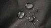 A close-up of water droplets on a dark, textured fabric. Produktbild-Vorschau