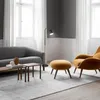 A modern living room scene with a grey sofa, an orange armchair and ottoman, and a floor lamp. Náhľad obrázku produktu