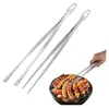 A hand is using a pair of stainless steel tongs to turn food on a grill. Produktbild-Vorschau