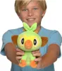 A young boy is holding a green plush toy. Produktbild-Vorschau