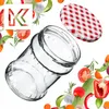 A glass jar and its lid are surrounded by various fresh vegetables and herbs, with a stylized letter 'K' in the top left corner. Anteprima dell’immagine prodotto