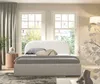 A bed with plush bedding in a bright, airy bedroom with two windows. Anteprima dell’immagine prodotto
