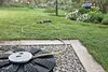 A garden sprinkler system watering a lawn with flowers in the background. Anteprima dell’immagine prodotto