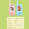 Two children's walkie-talkies, one pink and one blue, displayed against a light green background with a table of product specifications below. Produktbild-Vorschau