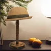 A hat stand with a hat on it, placed on a table with oranges and a lamp in the background. Produktbild-Vorschau