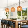A dining room with a wooden table and chairs, illuminated by three rattan pendant lights. Produktbild-Vorschau