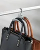 A handbag organizer hook holding two handbags, hanging from a closet rod. Produktbild-Vorschau