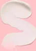 A swatch of white cream on a pink background. Voir les images du produit