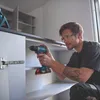 A man is using a cordless drill to assemble a cabinet. Voir les images du produit