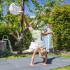 A young girl is doing a handstand in a backyard on a sunny day. Produktbild-Vorschau
