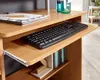 A close-up view of a wooden computer desk with a keyboard on a pull-out tray and some books on a shelf below. Anteprima dell’immagine prodotto