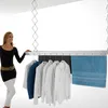 A woman stands next to a ceiling-mounted clothes drying rack with clothes and a towel hanging on it. Produktbild-Vorschau