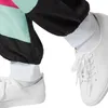 Close-up of a person's legs wearing a retro tracksuit and white sneakers. Produktbild-Vorschau
