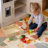 A toddler plays with a wooden toy kitchen set and toy food on a colorful play mat. Náhľad obrázku produktu