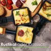 A close-up overhead view of a raclette grill with food being cooked in individual pans, along with some ingredients like tomatoes, salami, and cheese. Produktbild-Vorschau