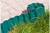 A roll of green garden edging is placed along the edge of a paved pathway and grass. Produktbild-Vorschau