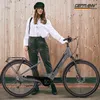 A woman stands next to an e-bike in front of a wooden wall. Produktbild-Vorschau