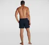 A man wearing navy blue swim shorts, viewed from the back. Produktbild-Vorschau