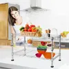 A woman is in a kitchen, smiling and standing behind a chrome shelving unit filled with kitchen items. Produktbild-Vorschau