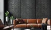 A living room scene with a brown leather sofa against a dark brick wall, featuring plants and a coffee table. Produktbild-Vorschau