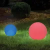 Two illuminated garden spheres, one blue and one red, sit on a grassy lawn at night. Produktbild-Vorschau