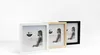 Three picture frames of different colors (white, wood, black) are displayed in a row against a white background. Voir les images du produit