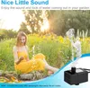 A woman in a yellow dress sitting by a garden fountain with water spraying. Produktbild-Vorschau