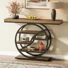 A console table with a geometric metal frame and wooden shelves, decorated with a vase of dried flowers, a bowl of apples, a lamp, books, and decorative objects. Anteprima dell’immagine prodotto