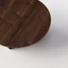 A close-up view of a round, dark brown wooden table top. Produktbild-Vorschau
