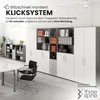 An office furniture display featuring modular shelving units and a table with chairs. Produktbild-Vorschau