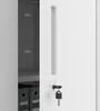 Close-up view of a white metal cabinet door with a key in the lock and a handle. The interior of the cabinet is partially visible, showing shelves and binders. Podgląd zdjęcia produktu
