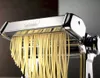 Close-up of a metal pasta maker producing fresh spaghetti. Náhled obrázku produktu