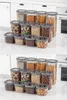 Two rows of clear plastic food storage containers filled with various food items and snacks, arranged on a white countertop. Produktbild-Vorschau