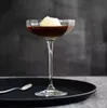 A cocktail with a scoop of ice cream on top, served in a coupe glass on a black tray with a spoon. Produktbild-Vorschau