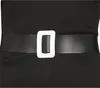 A close-up of a black belt with a white rectangular buckle on a black garment. Produktbild-Vorschau