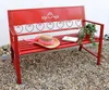 A red metal garden bench with decorative heart cutouts, adorned with a straw hat and a small potted plant. Produktbild-Vorschau