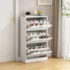 A white shoe cabinet with multiple shelves and doors, filled with shoes, placed in a hallway next to a door. Náhľad obrázku produktu