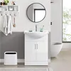 A modern bathroom vanity with a sink and cabinet, a round mirror above, and towels hanging on a shelf. Produktbild-Vorschau