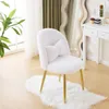 A white plush chair with gold legs and a heart-shaped pillow is placed on a white rug in a room with a large window and a vanity table in the background. Podgląd zdjęcia produktu