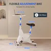 A white fitness bike with a laptop table attached, shown in a room with a light gray wall and a carpeted floor. Podgląd zdjęcia produktu
