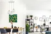A dining room and living room area with a pendant light fixture over a dining table and shelves with plants and decor in the living room. Produktbild-Vorschau